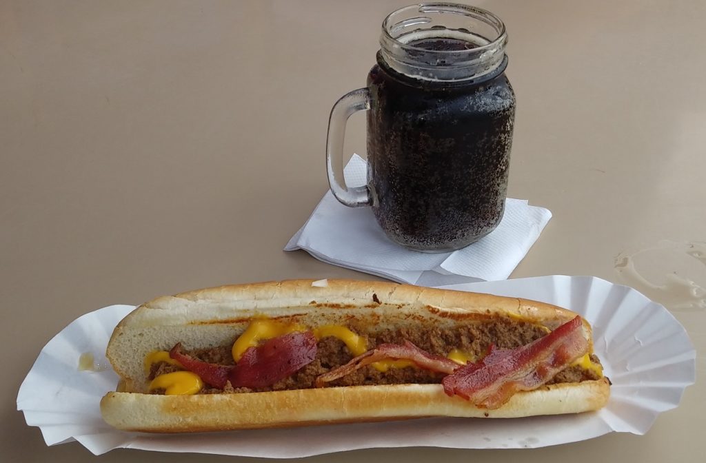 A bacon cheese foot-long Coney dog with a mug of root beer